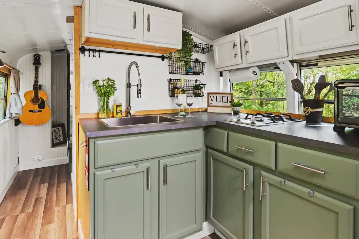 Green kitchen cabinetry and a window-lined worktop.
