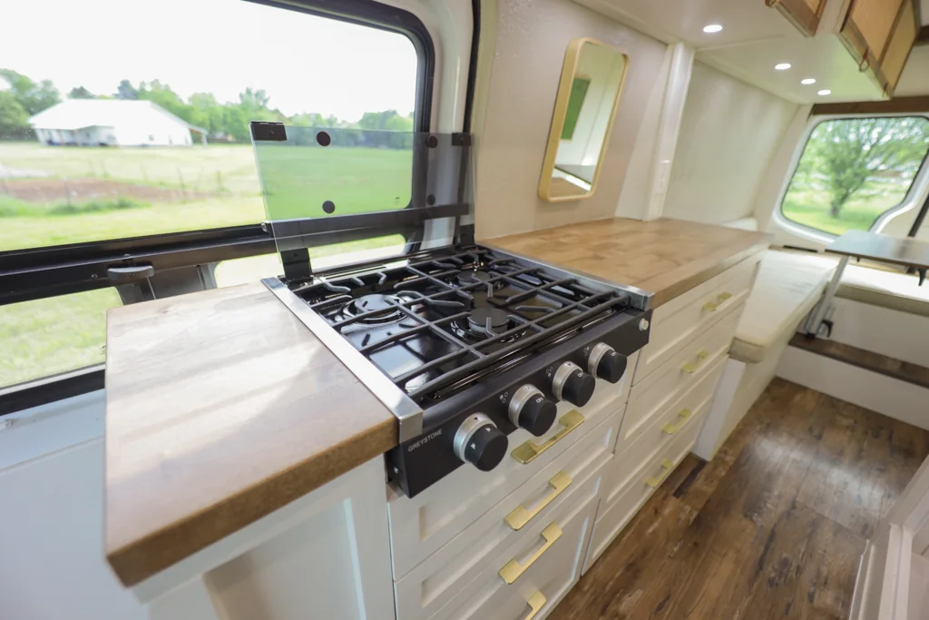 A three-burner propane cooktop alongside the kitchen window.